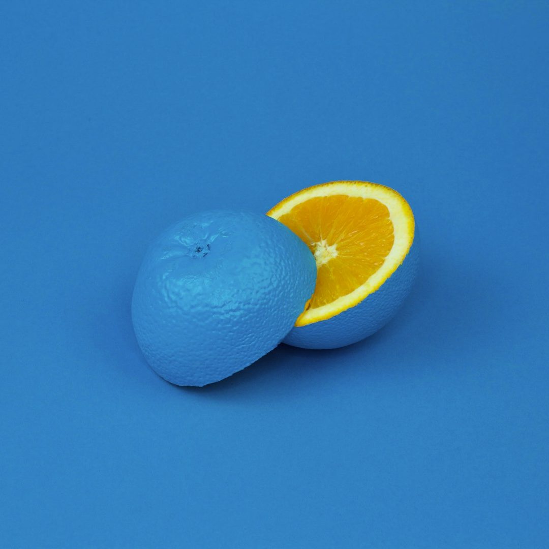A blue fruit resembling an orange, cut in half to reveal its orange interior.